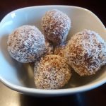 Snowball Cookies rolled in flaked coconut and piled in a white ceramic bowl