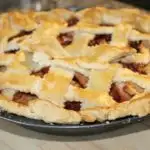 Freshly baked apple pie on wooden cutting board