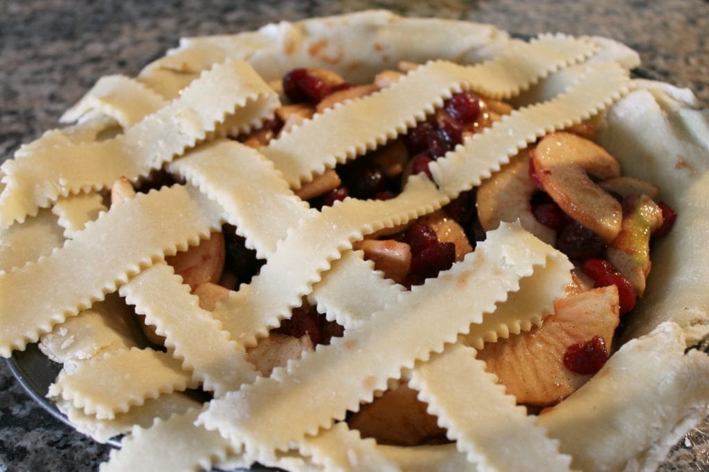 Uncooked cranberry apple pie with lattice top on counter top 