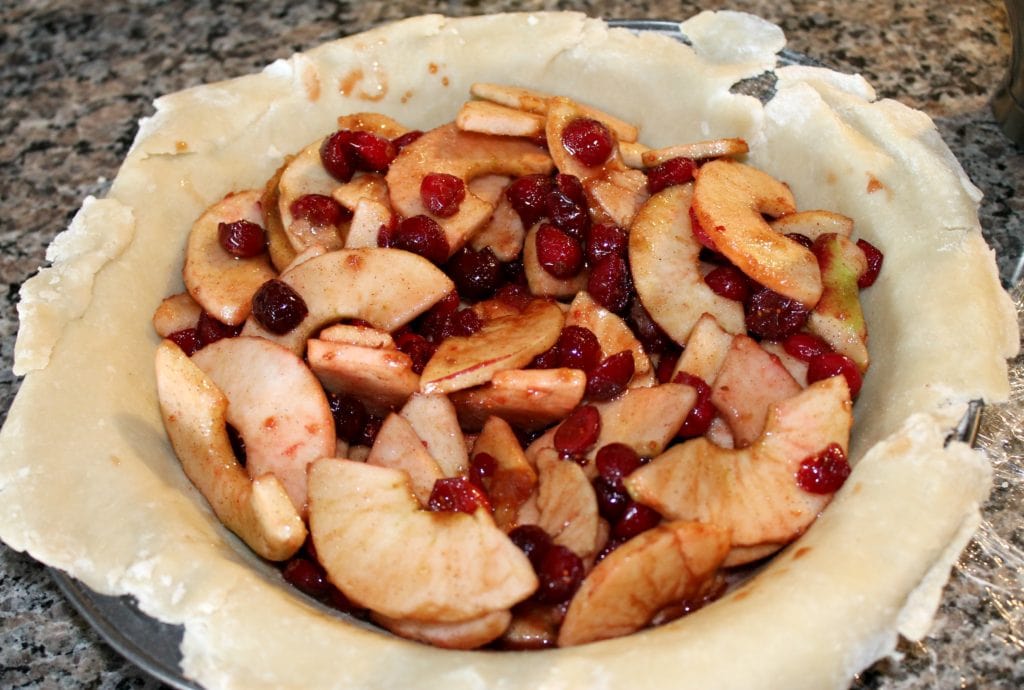 Open pie crust with chopped apples and cranberries