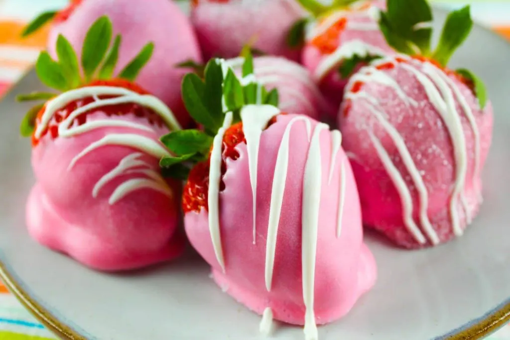 Pink chocolate covered strawberries on plate.