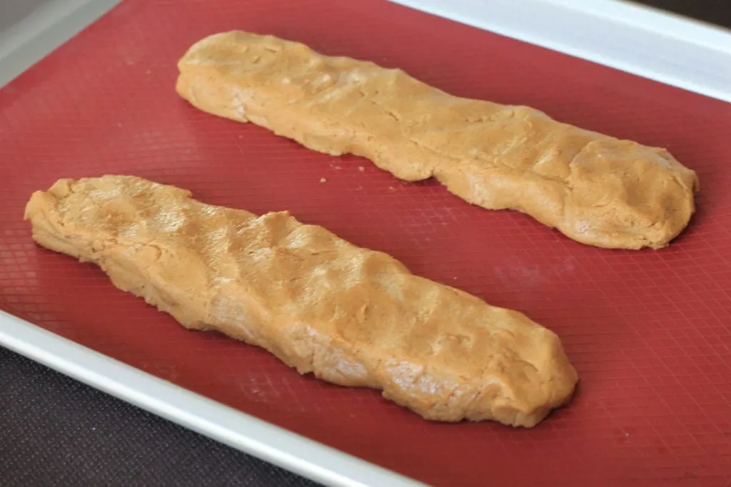 Two uncooked "logs" Gingerbread Biscotti on red silicone mat before going into the oven.