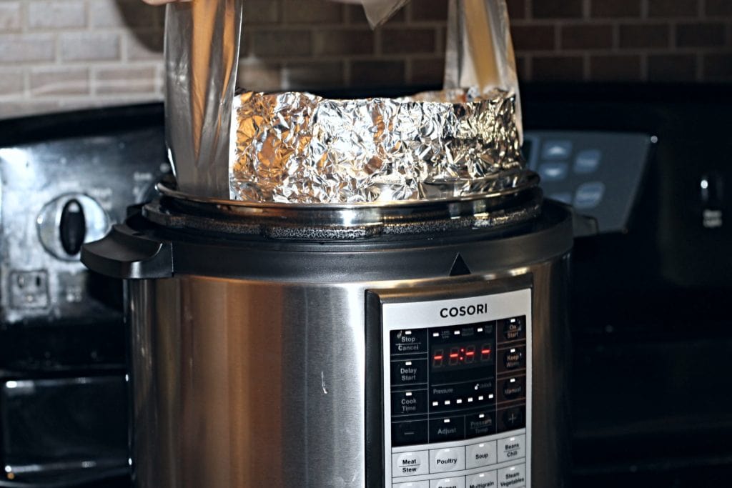 Foil Lift being used to gently lower pan into pressure cooker. Note we also wrapped the side of our pan to prevent spillage but this is not neccessary.