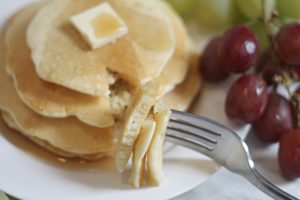 Forkful of pancakes with stack on plate