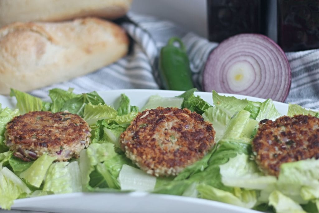 Tuna Cakes on top of a bed of lettuce on white platter