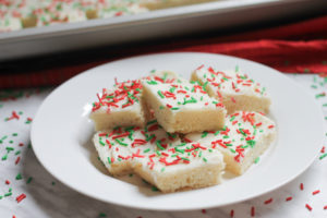 A white dessert plate piled high with frosted sugar cookie bars