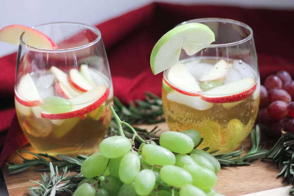 Two stemless wine glasses with white wine Christmas sangria and fresh grapes