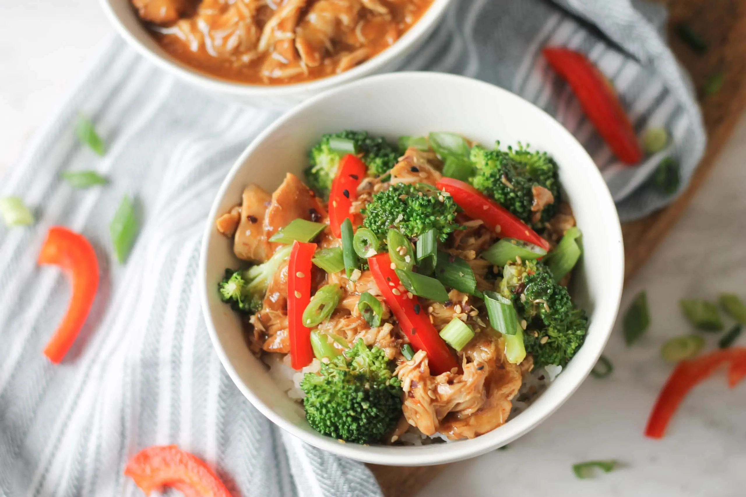 Bowl with garlic sesame chicken and steamed broccoli on table