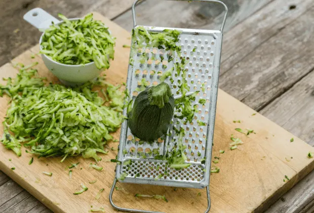 Wooden cutting board with grater and shredded zucchini