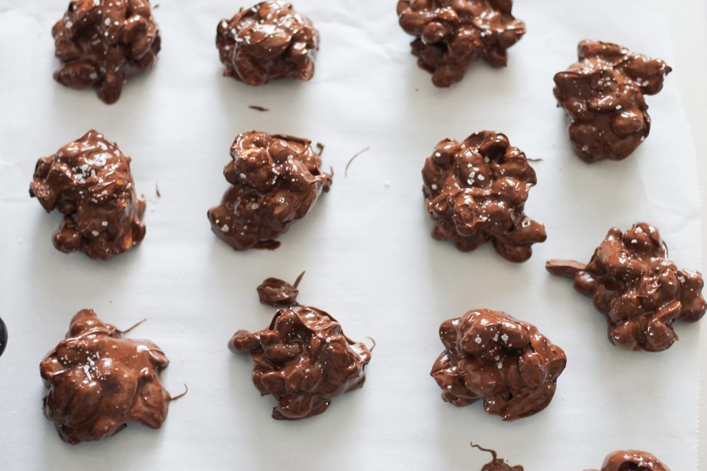 Scooped chocolate nut clusters on parchment lined sheets.